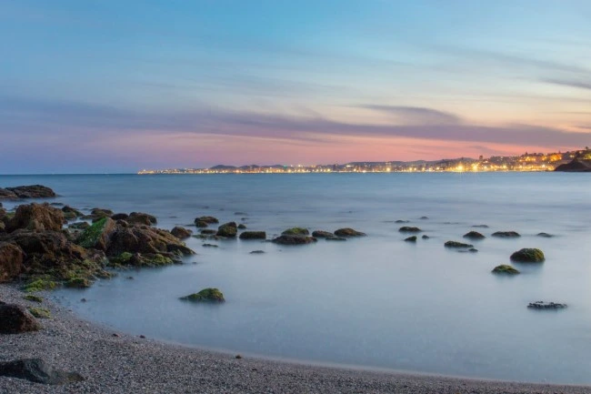 Rustige kust met rotsen in het water tijdens de schemering aan de Costa del Sol